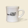 White mug with 'Route 66 New Mexico Magazine' text on a beige background